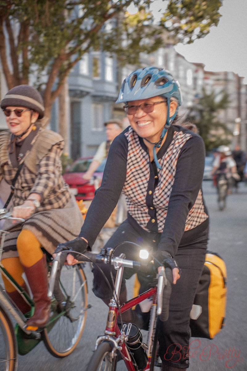 Two women ride bikes and smile