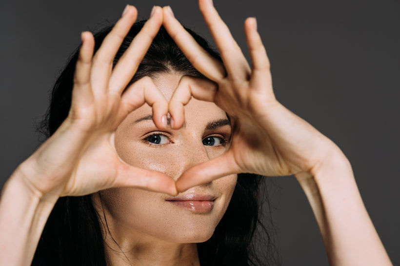 Beautiful tender woman showing heart sign isolated on grey background