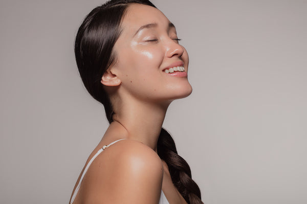 Young woman with Asian traits smiling with her eyes closed. 