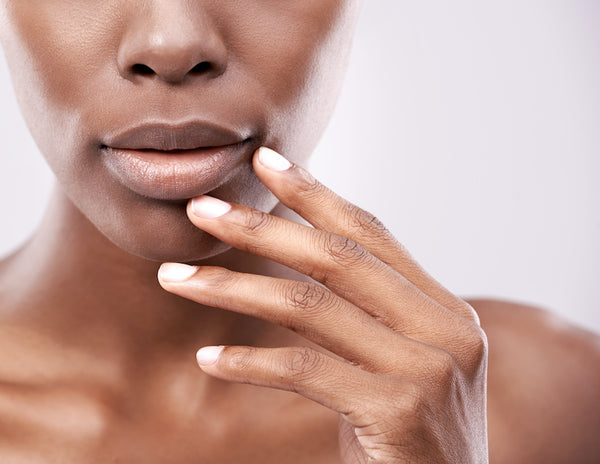 Cropped shot of a beautiful young woman against a gray touching her lucious lips