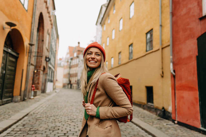 Photo of a young woman smiling  while travelling and exploring a city