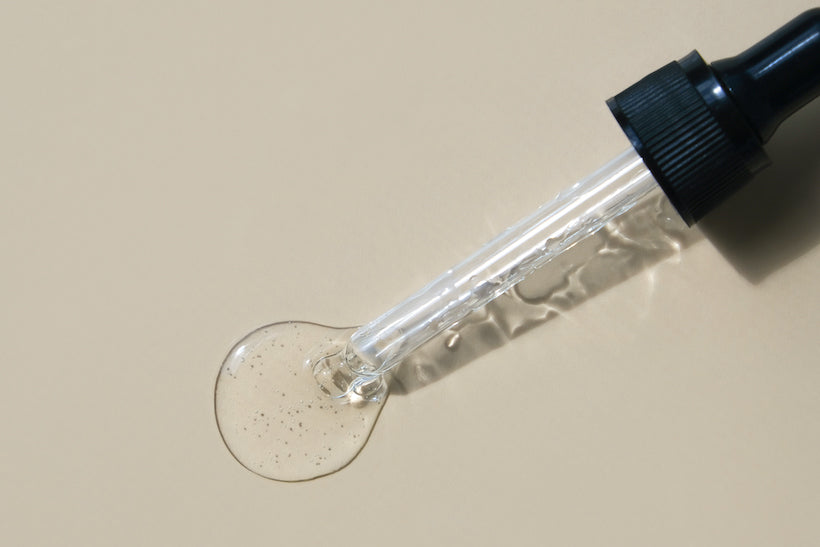 Dropper with clear ingredient on cream background