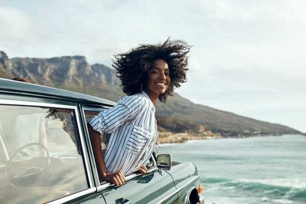 Shot of a happy young woman leaning out of a car window on a road trip