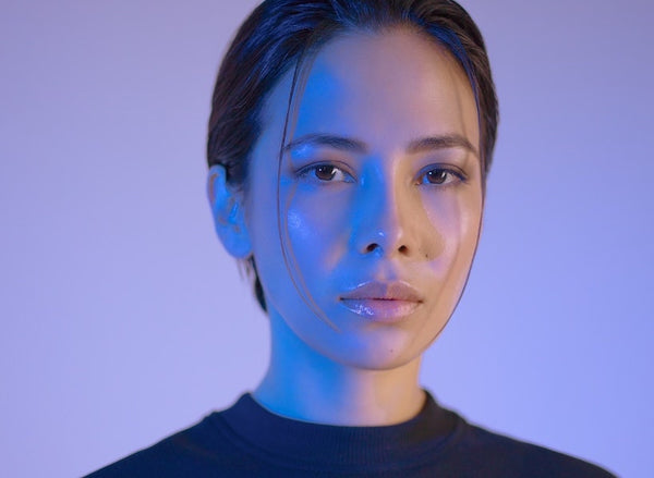 Woman with dewy, glowy skin on mauve background