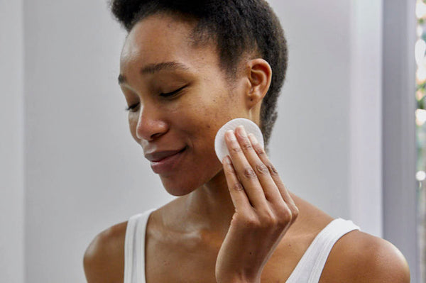 woman using a cotton pad to clean her skin
