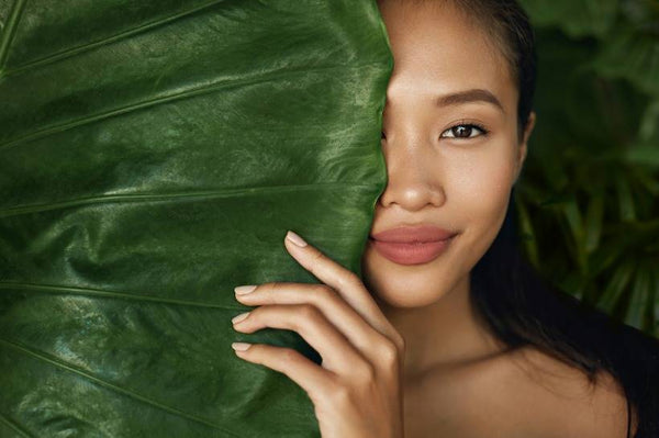 Woman smiling and peeking behind a leaf