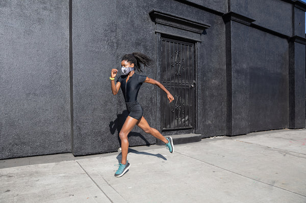 Fit African American woman running with a face mask. 