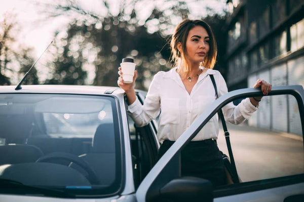 Woman getting into her car and holding a cup of coffee
