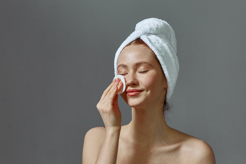 Young girl wipes face with cotton pad after shower stock photo