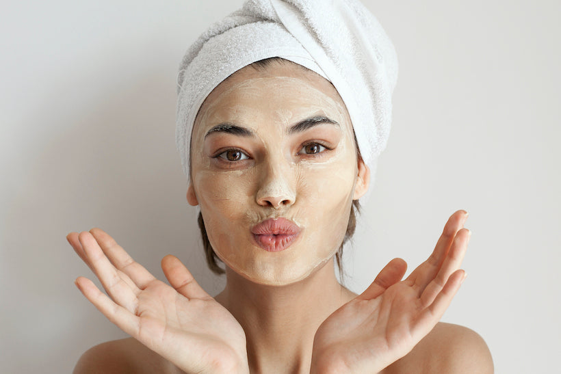 Woman with face mask and hair wrapped in towel