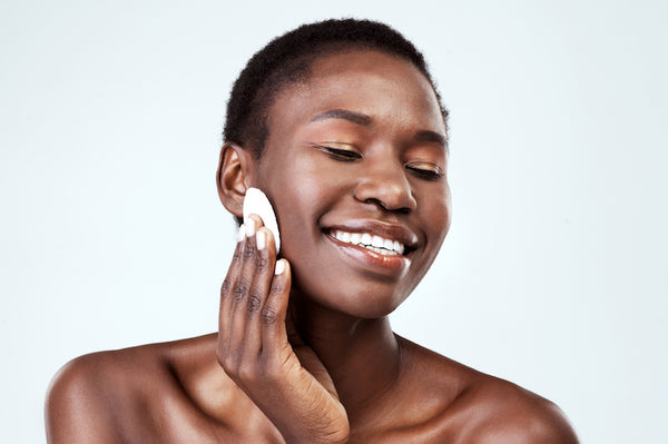 Woman wiping her face with a cotton pad.