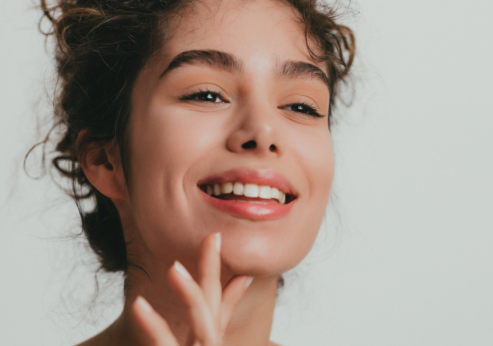 young brunette woman smiling and touching her chin