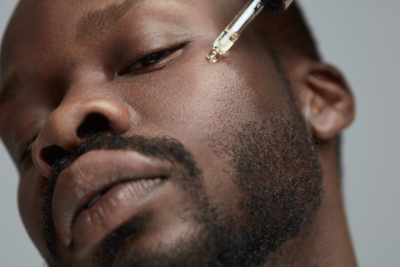 Male dark skin model close up with serum dropper on his face