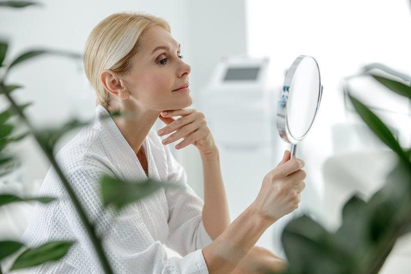 Smiling pretty woman using mirror