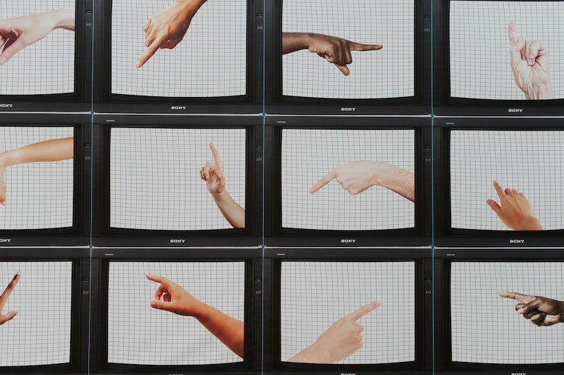Monitors displaying hands pointing in different directions stacked