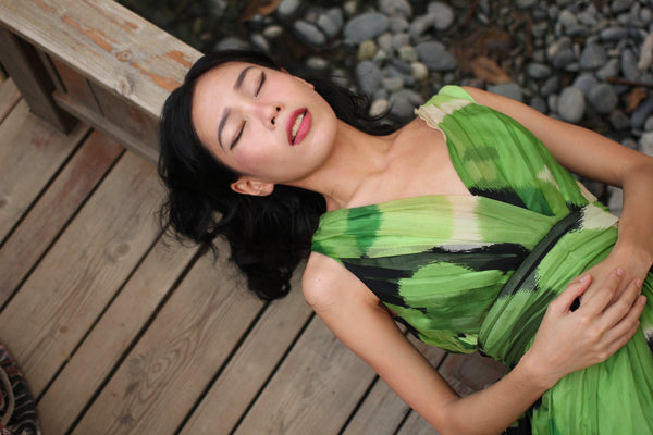 Woman in a green dress, lying down and relaxing.