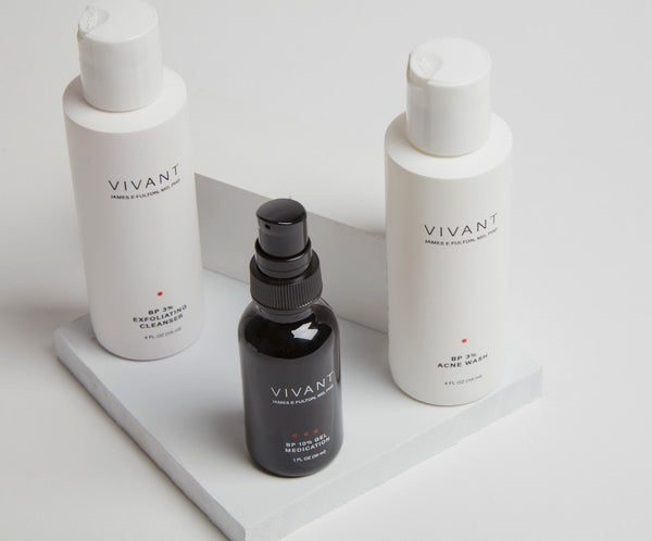 Vivant's benzoyl peroxide treatments. Two white bottles of cleanser and a serum in a black bottle. Studio shot.