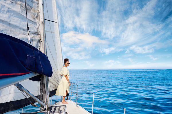 African American woman with yellow dress sailing and looking at sea