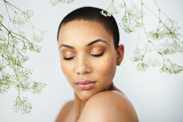 Light skin African American woman with eyes closed. Clear background with flowers hanging 