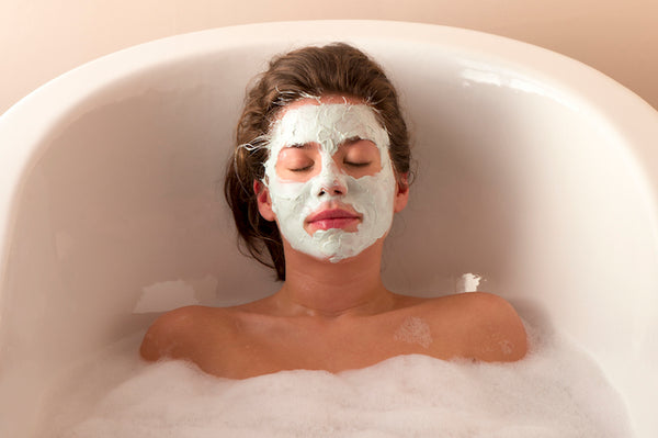 Woman relaxing in a tub with a face mask on.