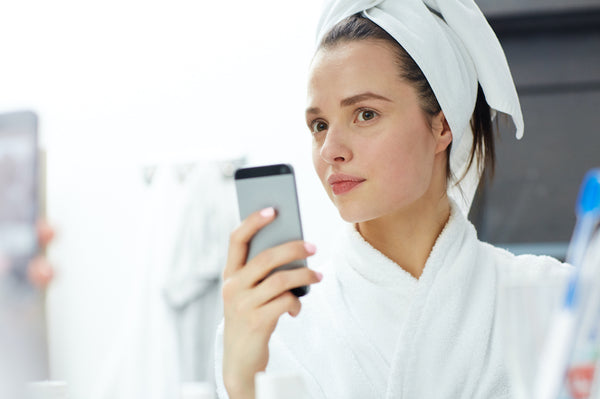 Young female with smartphone making her selfie in bathroom
