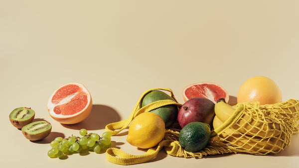 Fresh ripe fruits and string bag on brown background