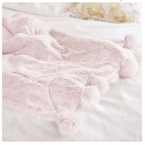 A pink furry blanket with pom poms