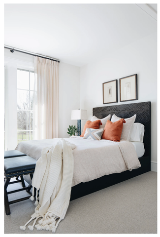 A light and airy bedroom with white bedding and orange pillows