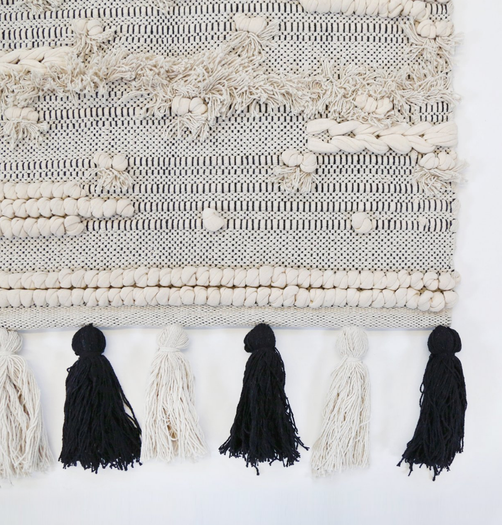 the corner of a handwoven rug with tassels