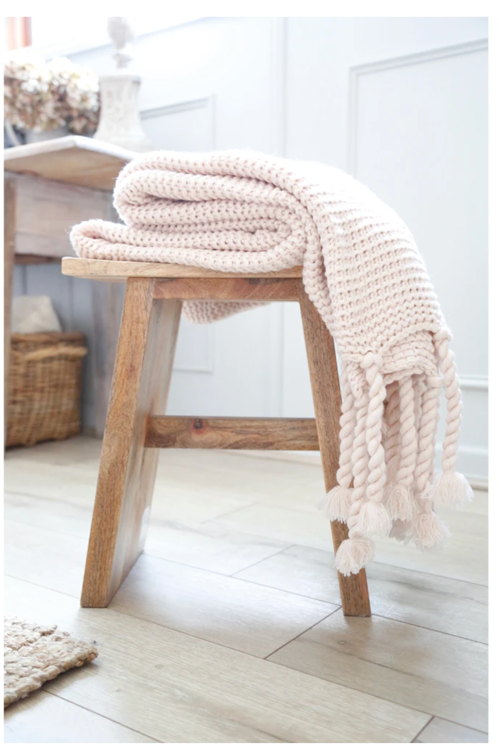 folded blush knit throw on wooden stool