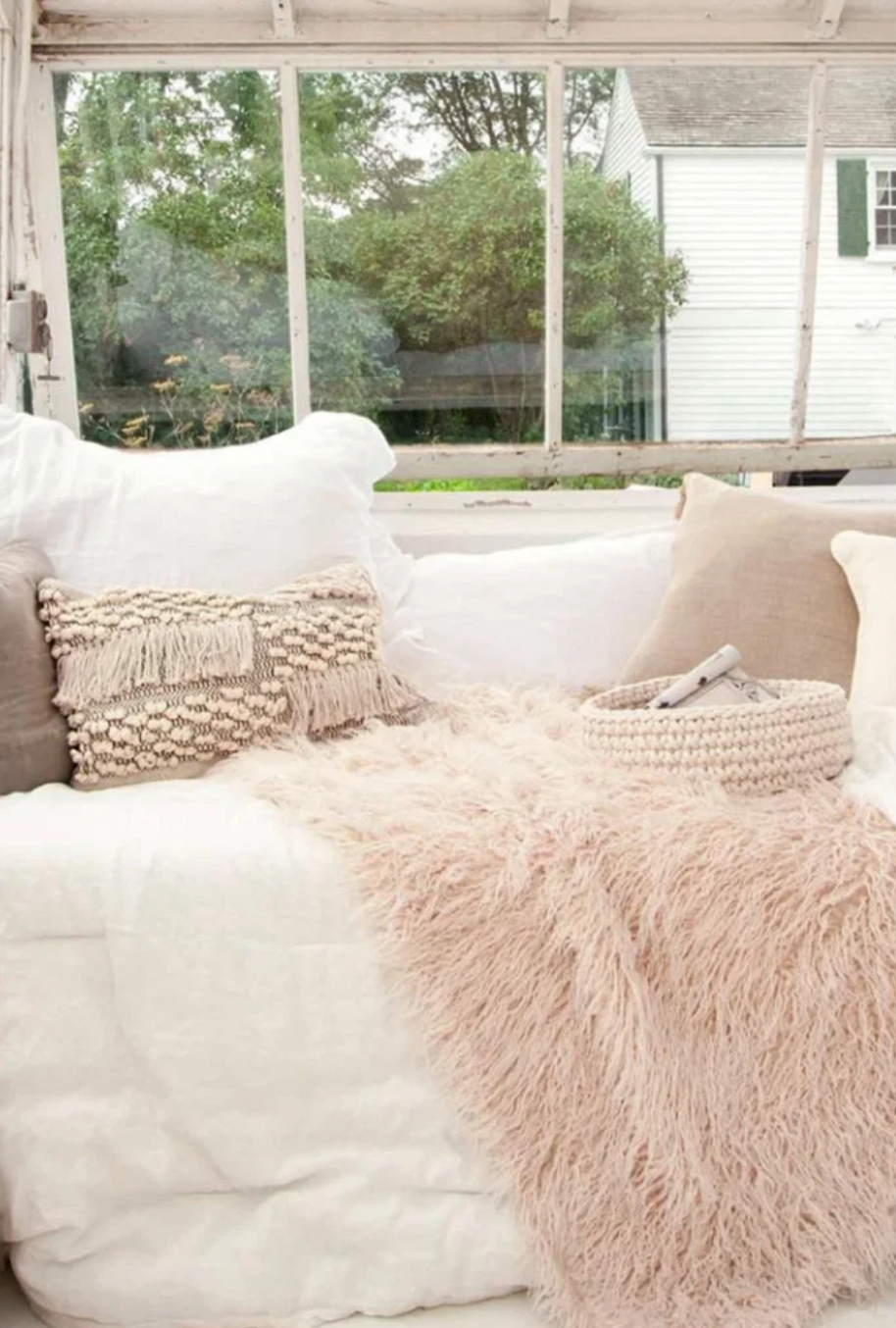 a bench in front of a window with shabby chic pillows and blankets on it