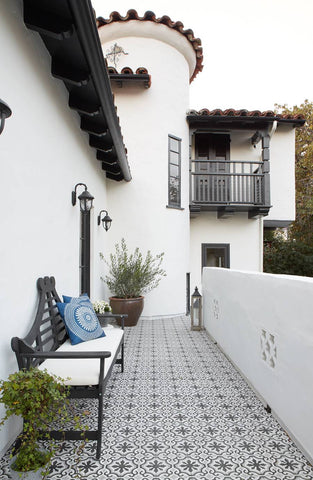 A spainish style home's tiled patio and white turret.