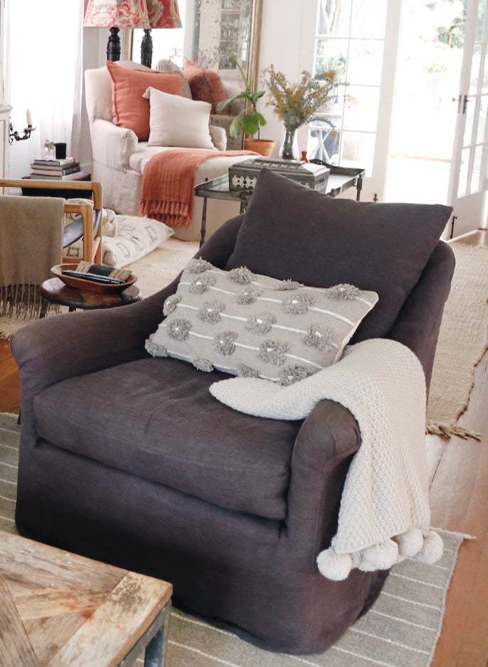 two comfy chairs in a living room with pillows and blankets