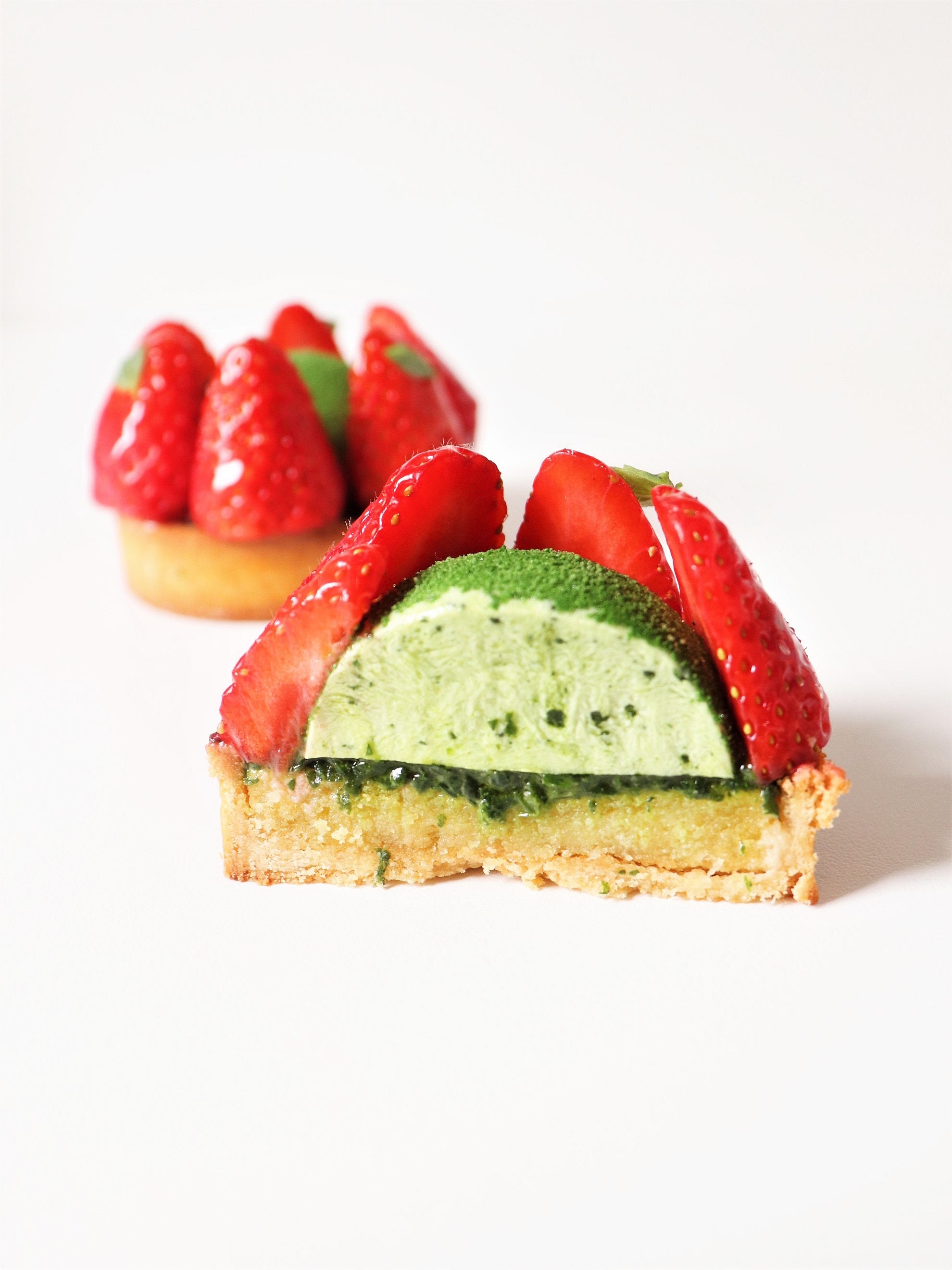 vue de découpe et tartelette entière aux fraises matcha et coulis de basilic roquette