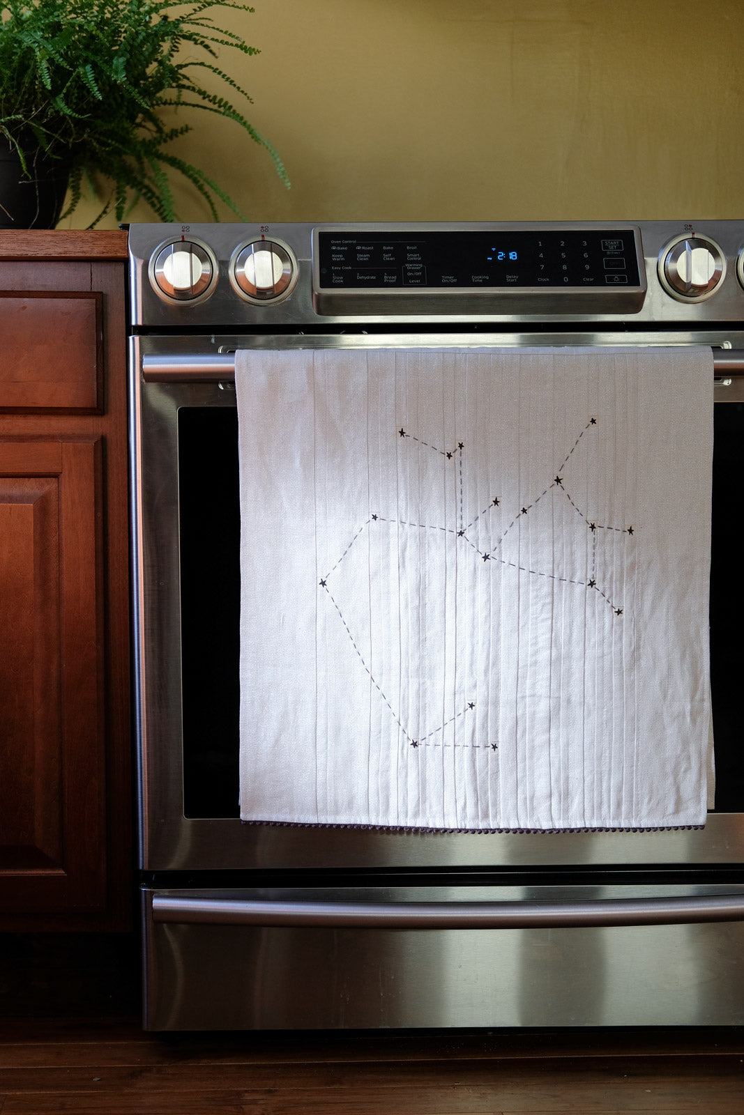 Astrological Tea Towel hanging from an oven handle