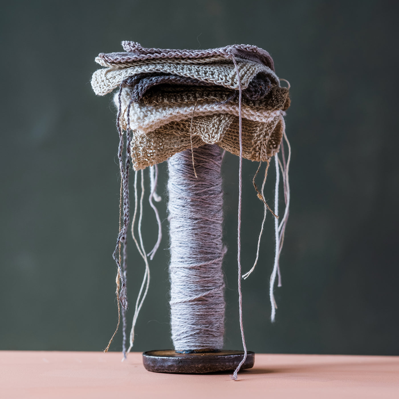 This is an image of several knitted swatches stacked on top of a ball of yarn