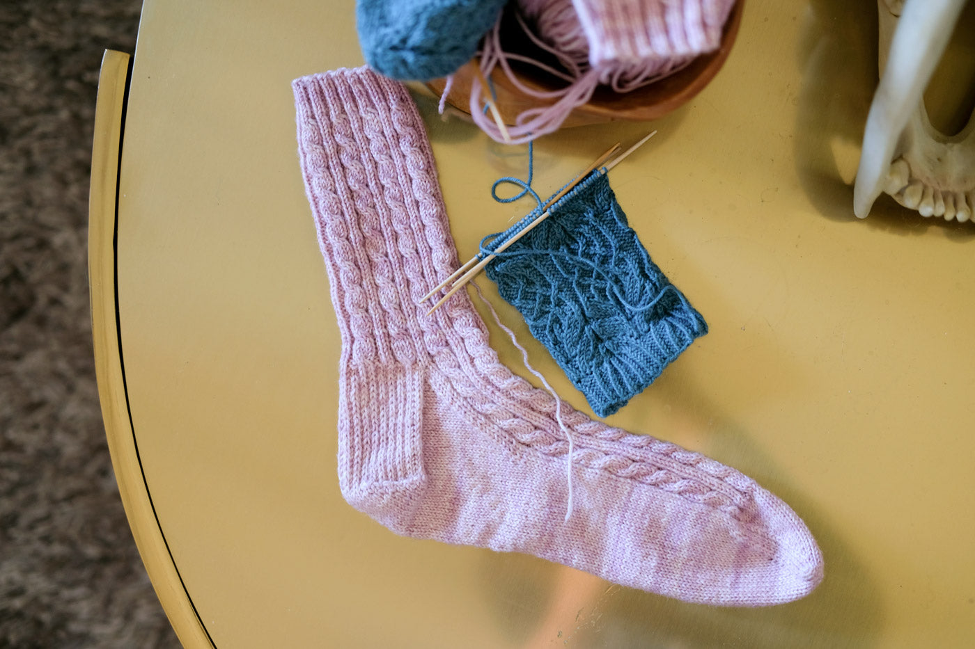 Partially knit socks on a gold table