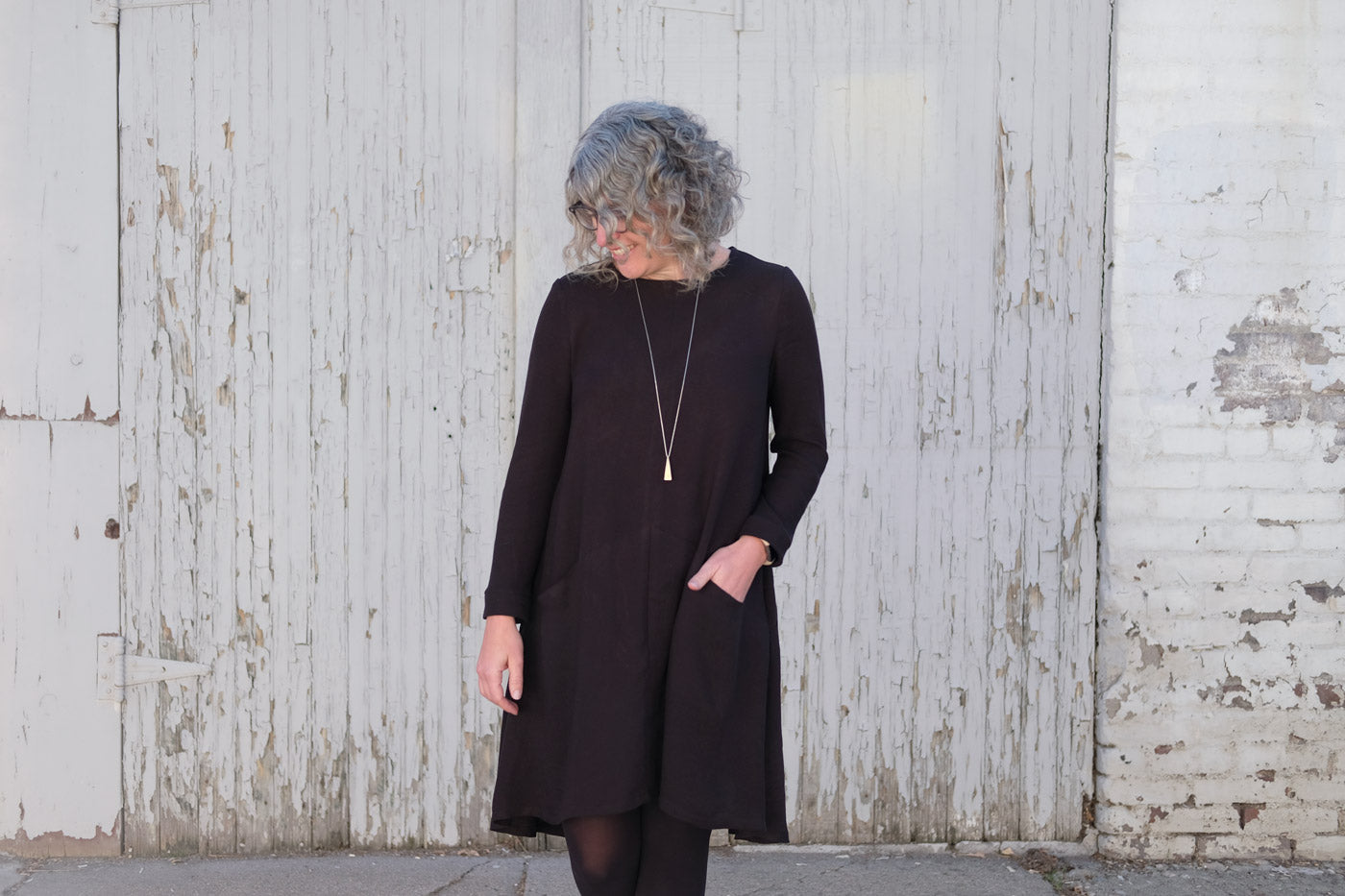 Jaime wearing her black Grainline Studio Farrow Dress and looking at the ground