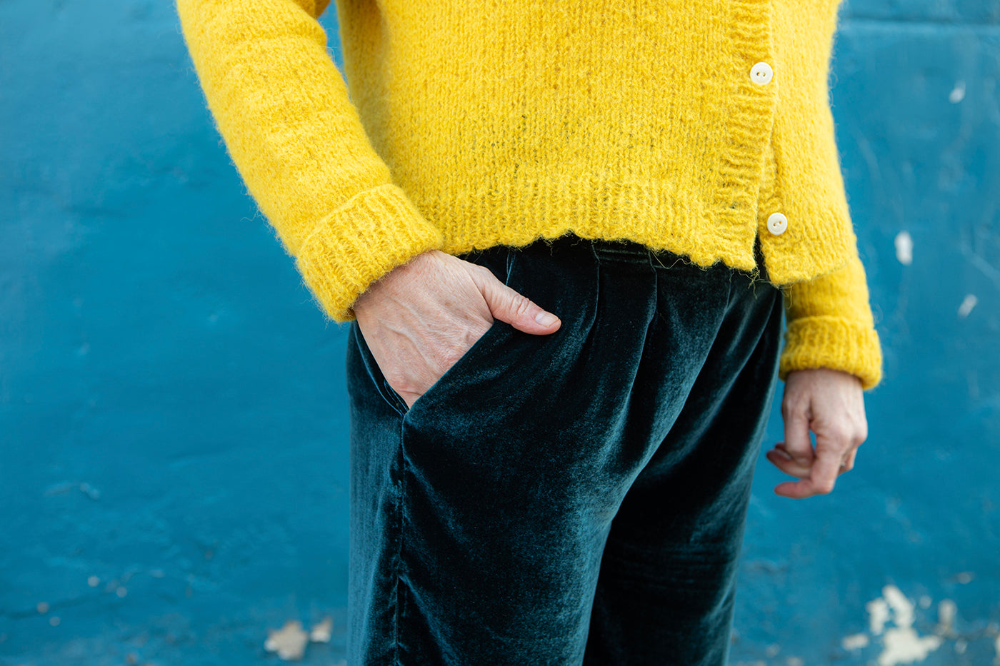 This is an image of a close up on Christina's hand placed in the front pocket of her Emerson Pants in Silk/Rayon Velvet in Peacock Blue.