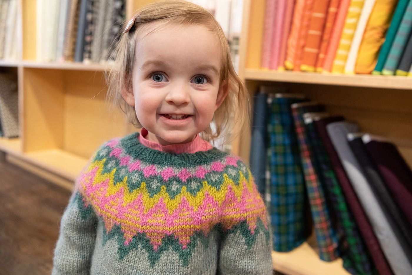 Caitlin's daughter wearing her Mini Kordy while standing in front of a shelf of fabric