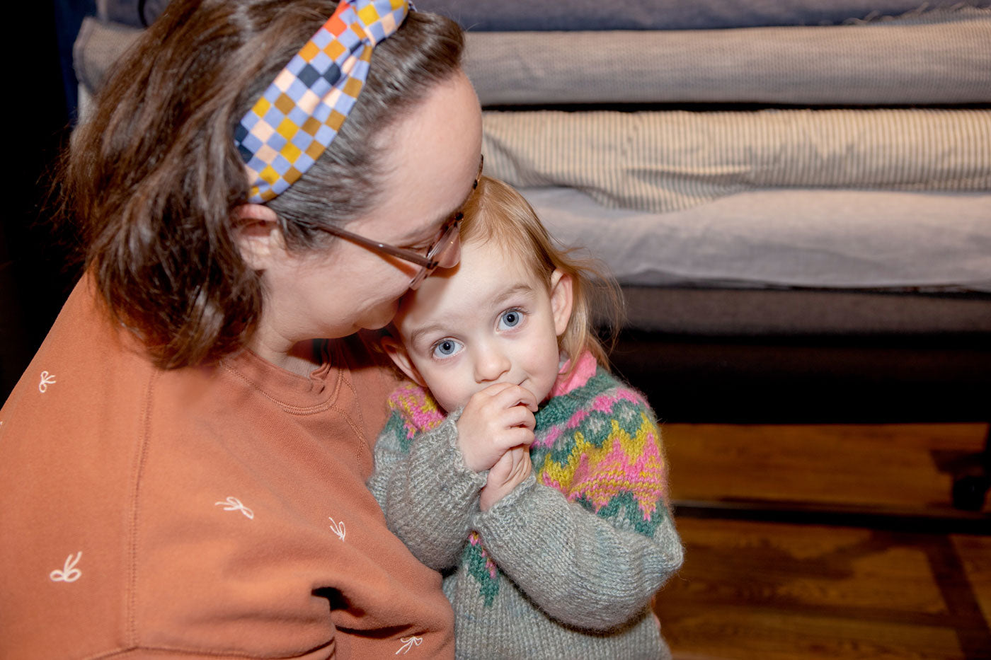 Caitlin embracing her daughter in front of a rack of fabric. 