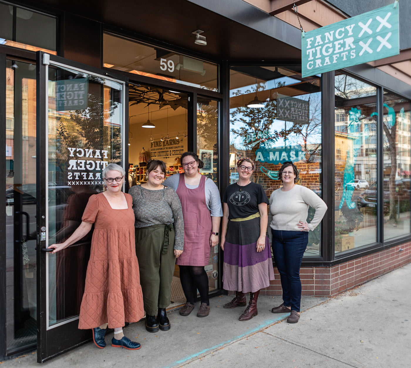 This is an image of members of the Fancy Tiger Crafts Co-op standing together in front of the store entrance. 