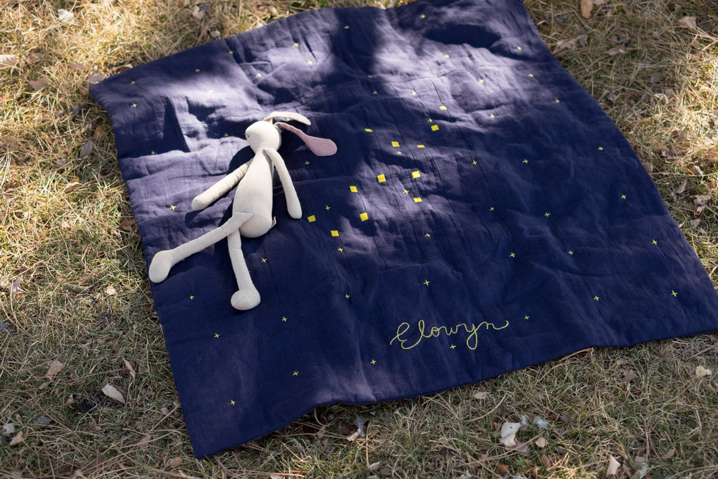 Sun dappled Constellation Quilt laying in the grass