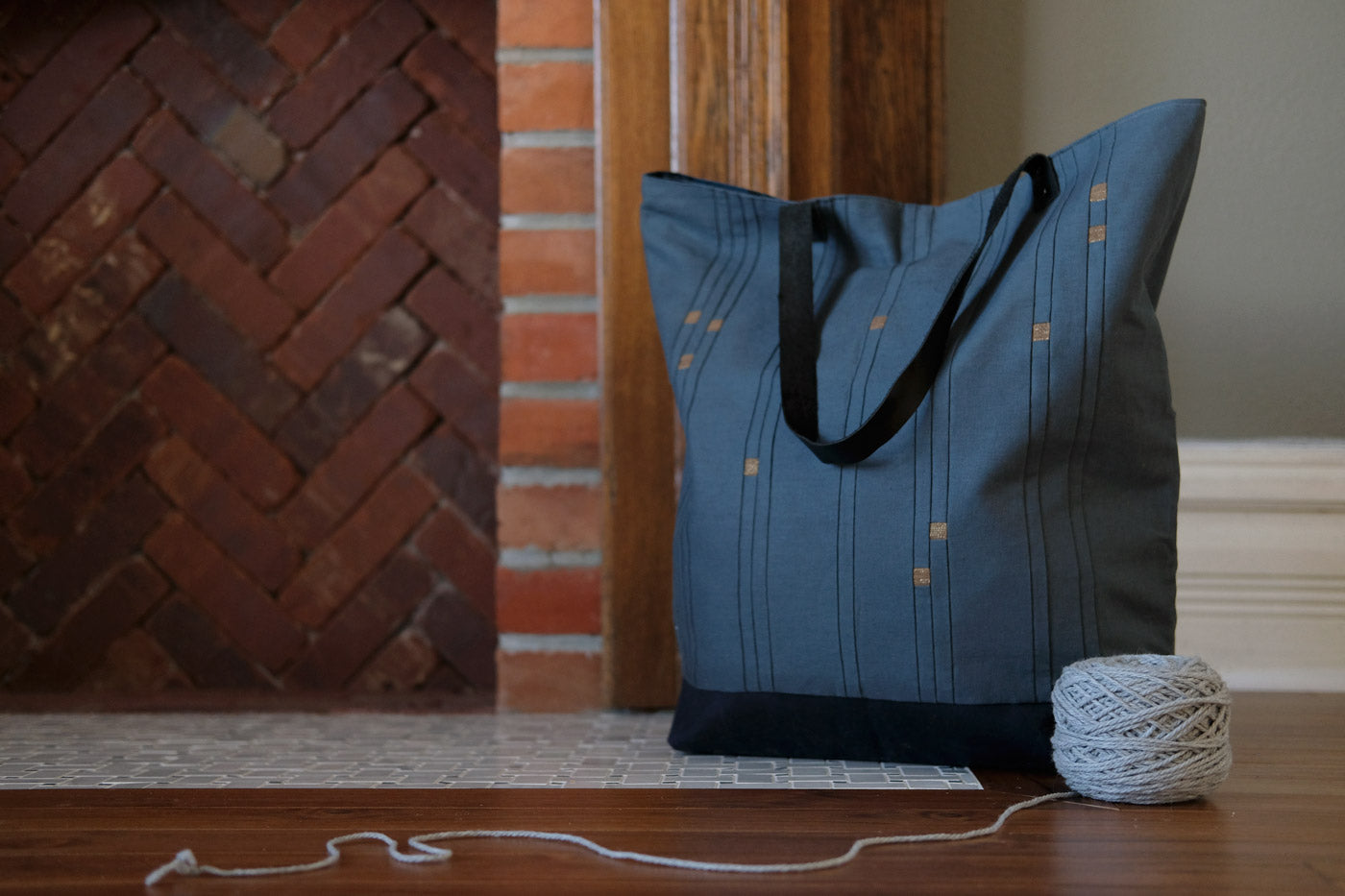 Blue Star Sign Tote sitting in front of a fireplace with a yarn ball next to it