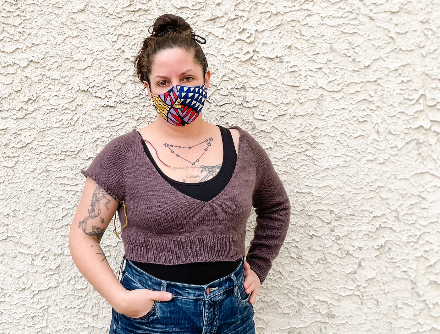 This is an image of a woman wearing a knitted sweater with one arm unfinished