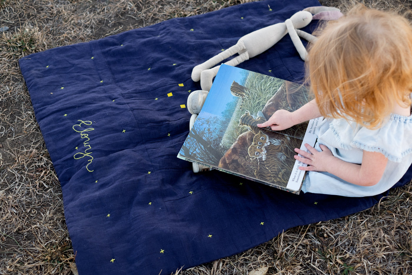 Elowyn reading a book on top of her Constellation Quilt