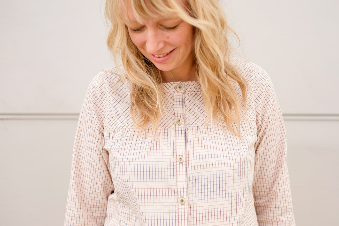 Detail of the yoke of the Brome button up. Woman looking down, the plaid on the yoke is on the bias, while the rest of the shirt, the plaid is on the straight grain.