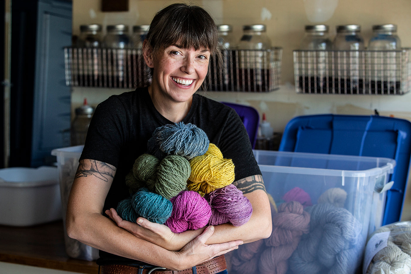 this is an image of a woman holding an armful of yarn skeins in different colors