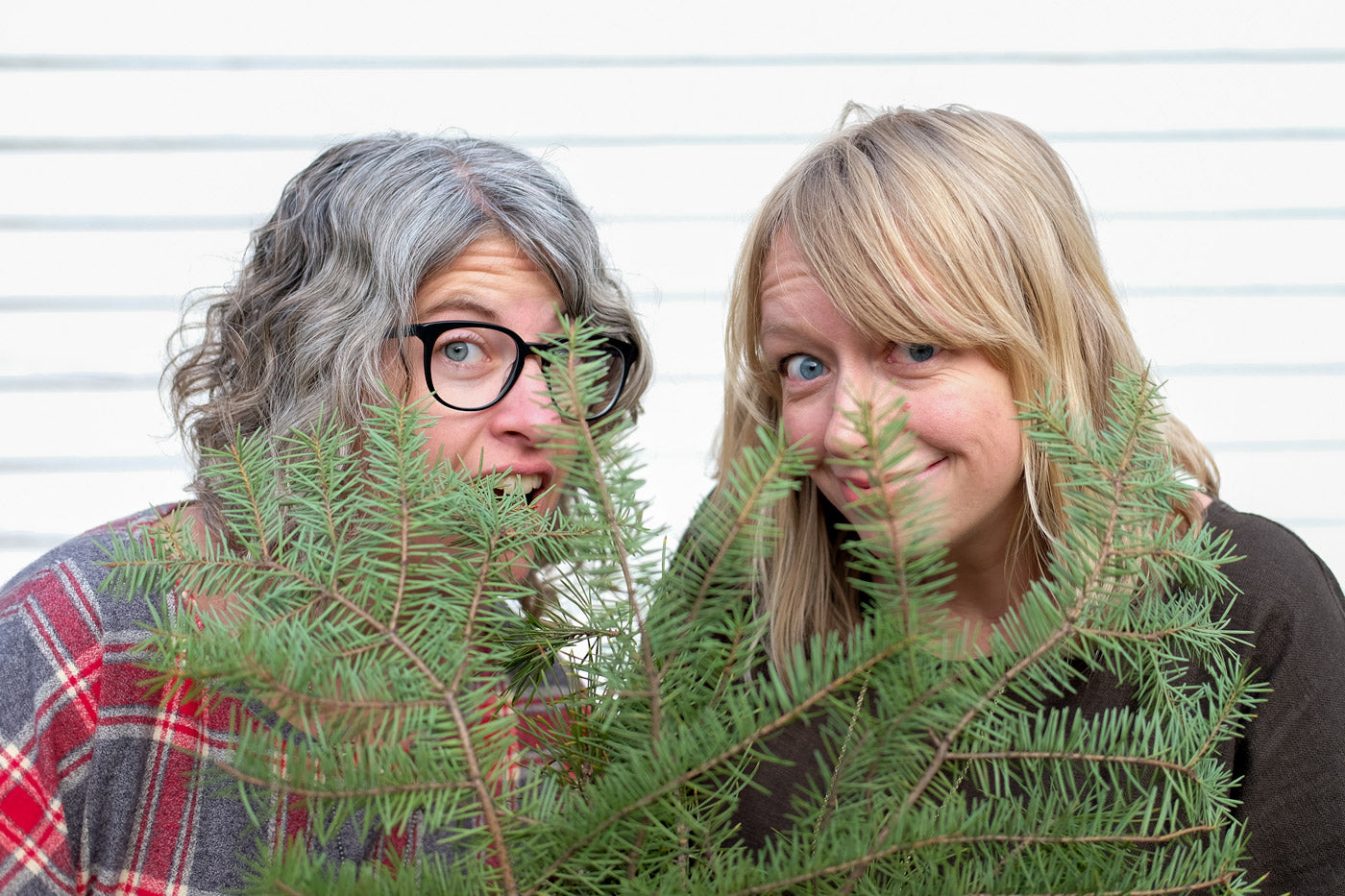 Jaime and Amber peeking out from some greenery