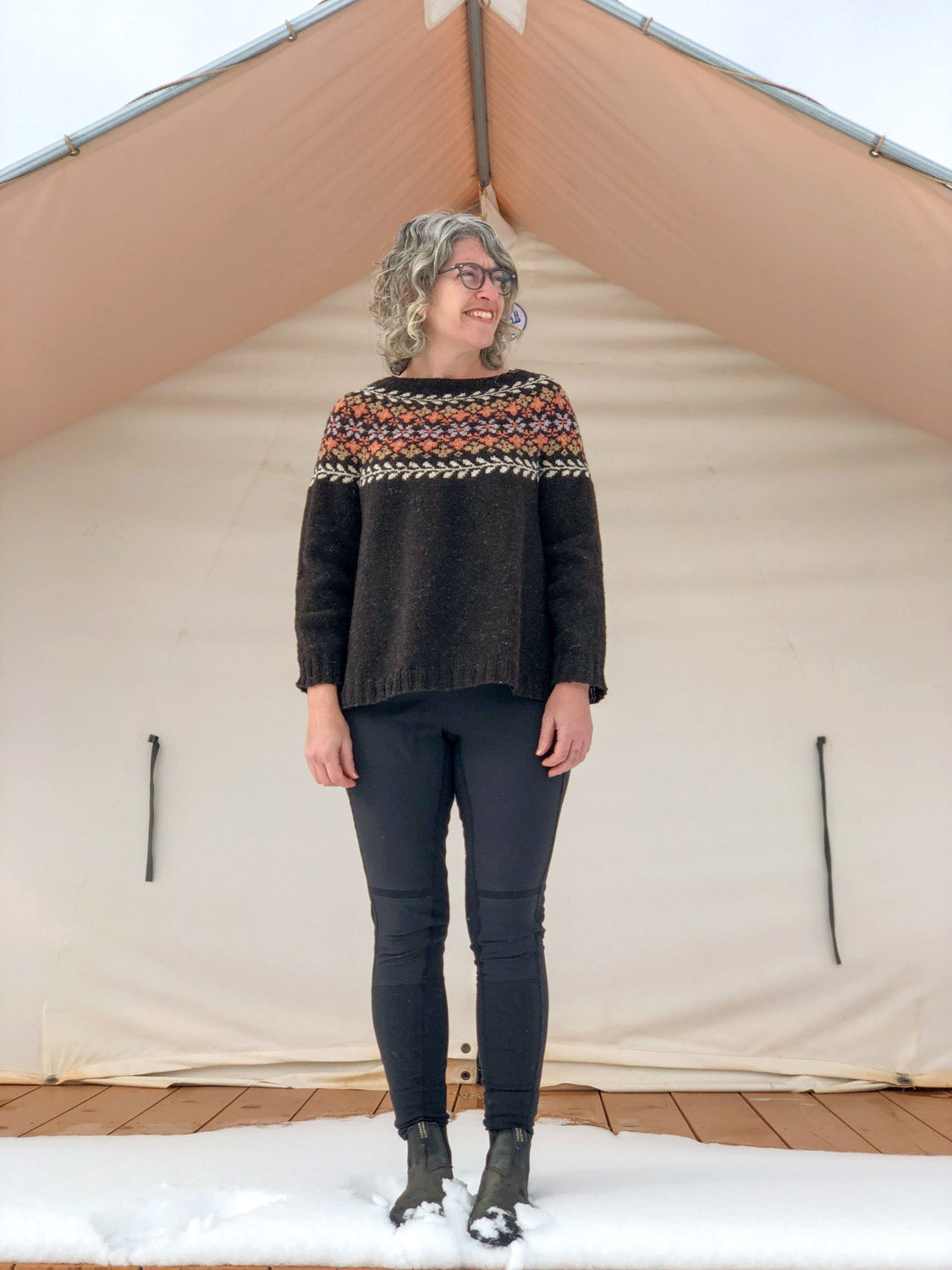 Jaime standing in front of a cream canvas tent in her freshly finished Birkin Sweater